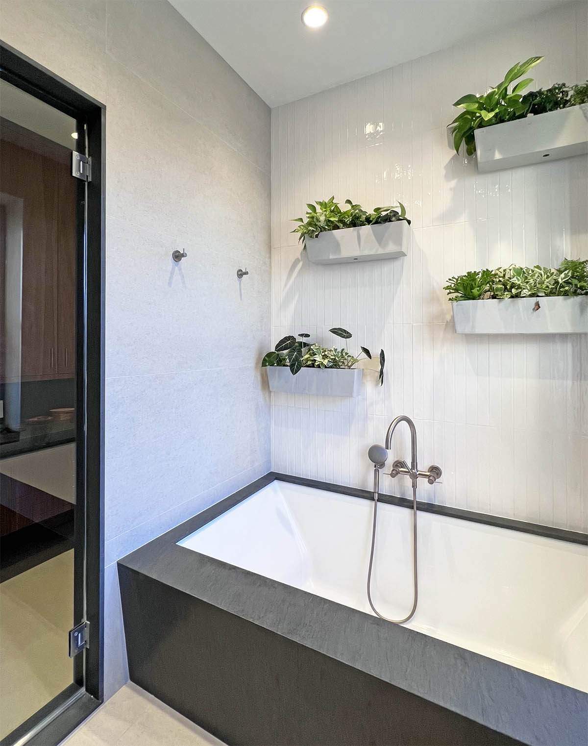 This photo shows a bathtub with wall hung plantings.